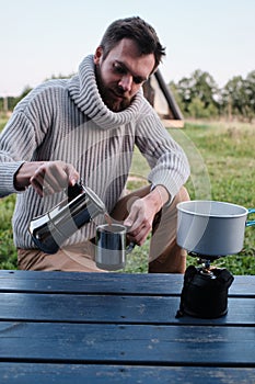 Young man pours coffee from a geyser coffee maker