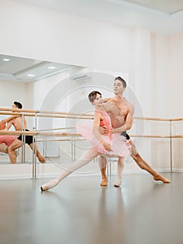 Young man practicing in classical ballet in the gym or ballet hall. Minimalism interior,