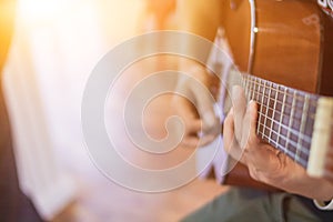 A young man is practicing playing guitar in a music practice room before performing in order to reduce the mistake of playing