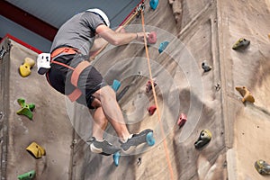 Young man practicing rock climbing on artificial wall indoors.