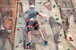 Young man practicing rock climbing on artificial wall indoors.