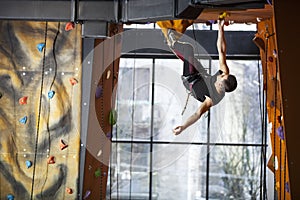 Young man practicing rock-climbing in climbing gym