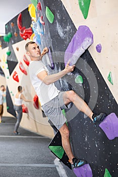 Young man practicing rock climbing on climbing wall