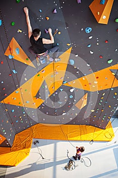 Young man practicing rock-climbing on a rock wall