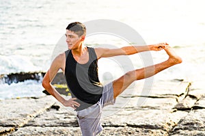Young man practicing yoga, doing Parivrtta Utthita Hasta Padangusthasana exercise, Twisting Extended Hand to Big Toe
