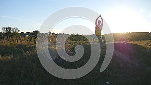 Young man practicing yoga moves and positions at hill at sunset. Sporty guy standing at yoga pose in nature. Beautiful