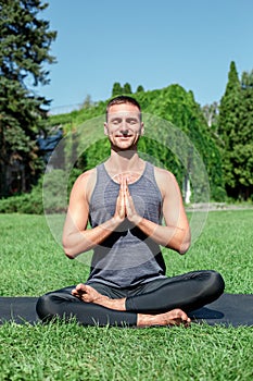 Healthy Lifestyle. Man practicing yoga outdoors sitting in lotus pose doing meditation smiling delightful