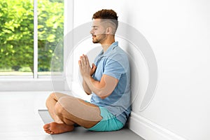Young man practicing zen yoga near wall
