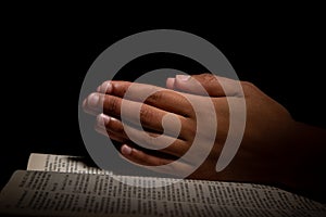 Young Man Praying with Hands on Top of the Bible