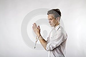 Young man is praying with rosary beads