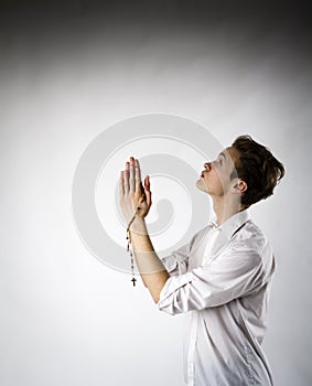 Young man is praying with rosary beads