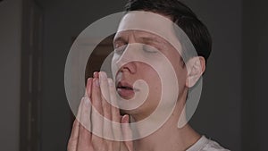 A young man praying to God. the prayer is performed in the house