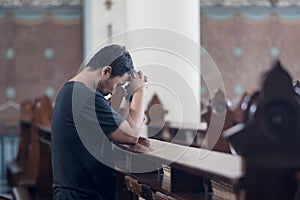 Young man prays with clasped hands in church