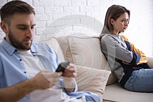 Young man preferring smartphone over girlfriend at home. Relationship problems