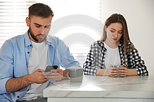 Young man preferring smartphone over his girlfriend at home. Relationship problems