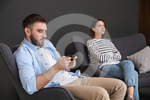 Young man preferring smartphone over his girlfriend at home. Relationship problems photo