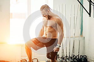 Young man preparing for barbell training in gym. put his leg on barbell