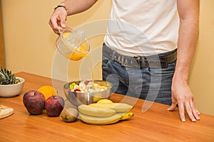 Young man preparing a fruit salad or smoothie