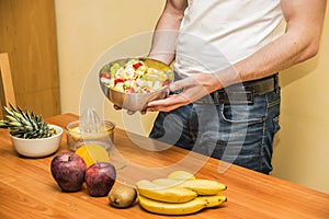 Young man preparing a fruit salad or smoothie