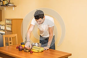 Young man preparing a fruit salad or smoothie