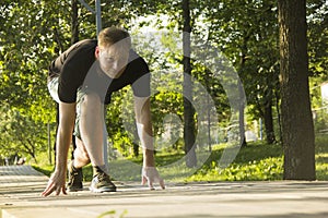 A young man is preparing for a run. The man is preparing to run from a low start. Jogging in the park