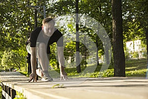 A young man is preparing for a run. The man is preparing to run from a low start. Jogging in the park. Blurred focus