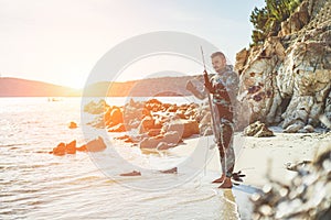 Young man preparing speargun for underwater fishing at sunset in italy - Male hunter getting ready for hunting wearing camouflage