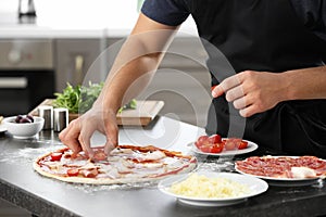 Young man preparing tasty pizza at table