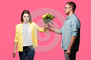 young man presenting bouquet of flowers to angry woman isolated