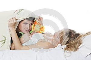 Young man presenting toy flower to girl in bed