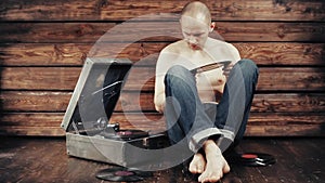 Young man pretending to listen to an old gramophone at home