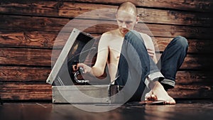 Young man pretending to listen to an old gramophone at home