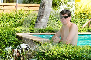 Young man in private tropical villa swimming pool