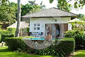 Young man in private tropical villa swimming pool