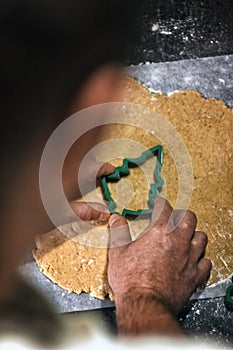 Young man in the process of baking Christmas dough, cutting gingerbread dough cookies. Festive mood. Family cooking