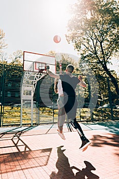 Young man with prosthetic leg playing basketball with his friend at a court