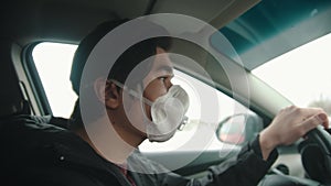 Young man in protective mask driving a car