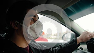 Young man in protective mask driving a car