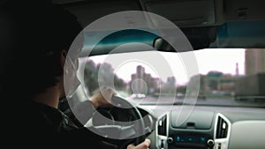 Young man in protective mask driving a car and looking in the windows