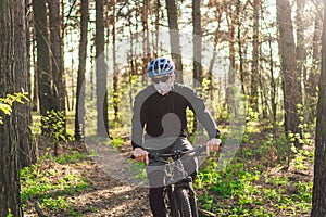Young man in protective mask from environmental pollution riding mountain bike on cross country road. Cyclist Riding the Bike on