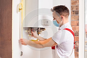The plumber repairs a boiler in a medical mask photo