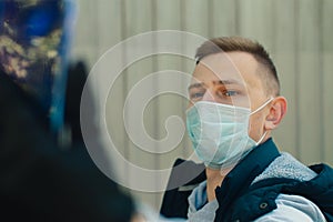 Young man in a protective mask using mobile phone for video conference on street