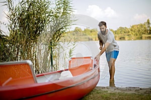 Young man pulling canoe into calm lake