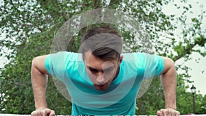 Young man pulls himself up on horizontal bar. Outdoor sports and workout