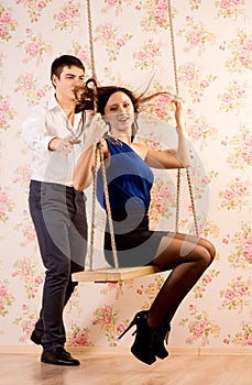 Young man pushing his sweetheart on a swing