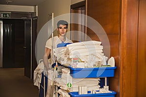 Young man pushing a housekeeping cart in a hotel