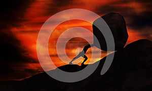 Young man Pushing uphill Big Rock At sunset. Businessman Push The Heavy Stone up the top of mountain. photo