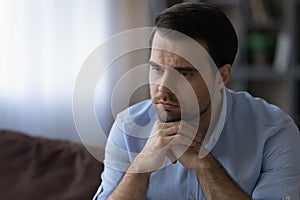 Young man put chin on hands lost in bad thoughts