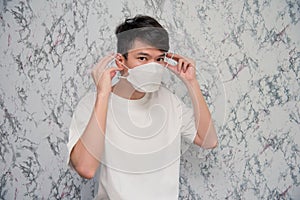 Young Man puts on a face mask protecting from virus during quarantine  on White background , Covid-19