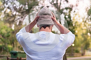 Young man puts on a hat to protect his head from the cold, he is on his back